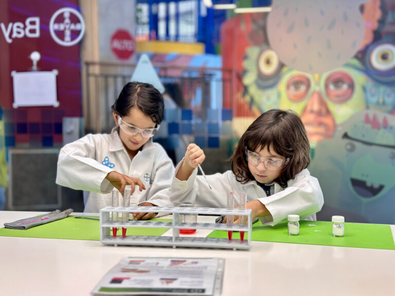 Niños en batas blancas realizando un experimento científico